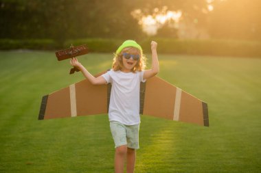 Çocuk günü. Mutlu çocuk dışarıda oynuyor. Çocuk kağıt kanatlarla eğleniyor.