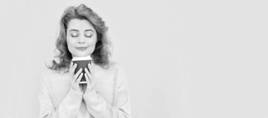 Woman isolated face portrait, banner with copy space. happy redhead woman smelling takeaway coffee from cup on yellow background, good morning