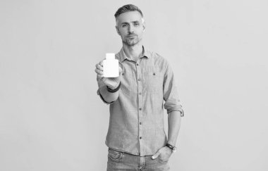 man hold pill jar on yellow background, health.