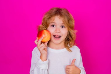 Elma. Stüdyoda elmalı çocuk. Stüdyo portresi pembe arka planda izole edilmiş elma tutan şirin çocuk.