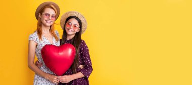 Anne ve kız çocuk afişi, kopyalama alanı, izole bir arka plan. Sarı arka planda aşk balonu tutan neşeli anne ve kız
