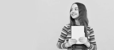 Happy girl child smile holding book yellow background. Portrait of schoolgirl student, studio banner header. School child face, copyspace