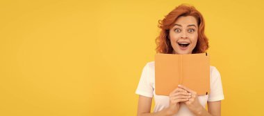 Şaşırmış bir kız sarı arka plan ve okul defterini tutuyor. İzole edilmiş yüz portresi, kopyalama alanı olan pankart