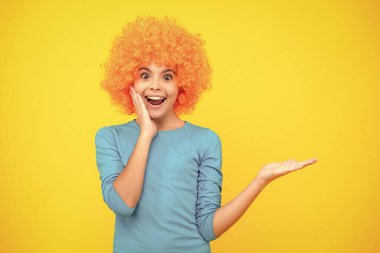 Funny kid in curly redhead wig. Time to have fun. Teen girl with orange hair, being a clown. Excited teenager, glad amazed and overjoyed emotions