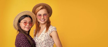 Mother and daughter kid banner, copy space, isolated background. smiling mother and child in straw hat on yellow background