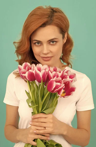 young woman with tulip flower bouquet on blue background.