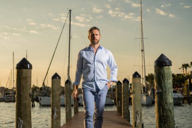 40 'lı yılların adamı yatın yanında. Dışarıdaki mankenin portresi. Moda erkeği yatların yanında poz veriyor. Şehir tarzında bir moda adamı. Yat kulübündeki yakışıklı İspanyol adam. Lüks yatın yanındaki körfezdeki adam.