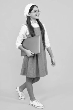 Young girl student hold computer. Funny pupil with laptop isolated on yellow background. Back to school. Happy face, positive and smiling emotions of teenager schoolgirl