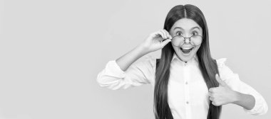 Şok olmuş uzun saçlı çocuk inek gibi görünüyor. Başparmağını kaldır. Genç kız gözlüklerinden bakıyor. Çocuk yüzü, yatay poster, izole edilmiş genç kız portresi, fotokopi alanı olan pankart