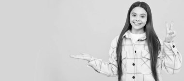 Mutlu kız pembe kareli gömlek giyer ürün sunar, fotokopi alanı oluşturur, promosyon yapar. Çocuk yüzü, yatay poster, izole edilmiş genç kız portresi, fotokopi alanı olan pankart