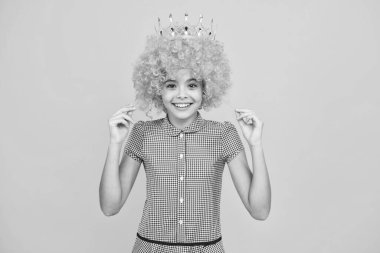 Portrait of ambitious teenage girl in wig with crown, feeling princess, confidence. Child princess crown on isolated studio background