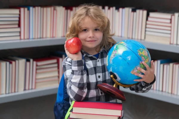 Cute pupil looking at globe in library at the elementary school. School child. Kid boy from elementary school. Pupil go study. Clever schoolboy learning. Kids study, knowledge and education