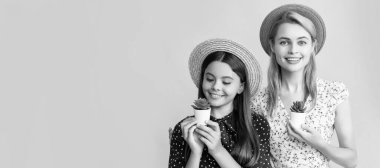 Mother and daughter kid banner, copy space, isolated background. positive mother and daughter with plant in pot on yellow background
