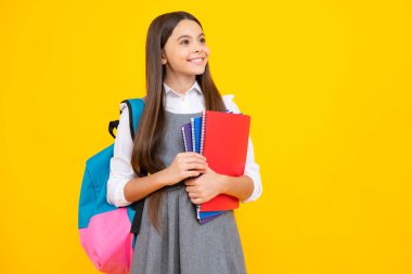 Liseli kızın elinde sarı izole edilmiş stüdyo geçmişi ile ilgili defter ve kitap var. Okul ve eğitim kavramı. Okul üniformalı ergen kız.