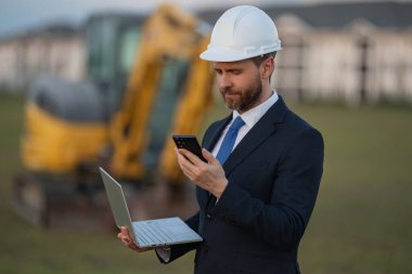 Kazıcının yanında inşaat işçisi. Evin önünde kendine güvenen bir inşaat sahibi. Mimar, inşaat mühendisi. İnşaat alanında güvenlik yeleği ve kasketi olan bir inşaat sahibi.