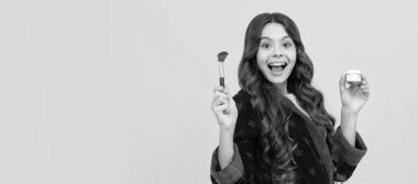 happy kid girl in sleepwear using cosmetic brush and powder foundation. Cosmetics for teenager child, poster design. Beauty kids makeup, banner with copy space