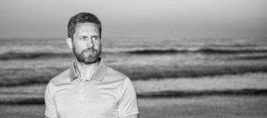 Man face portrait, banner with copy space. charismatic man with beard in sunset over sea. unshaven guy on morning beach