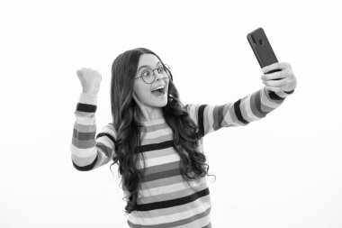 Kids selfie. Portrait of excited teenage girl using mobile phone, chatting on web, typing sms message. Mobile app for smartphone