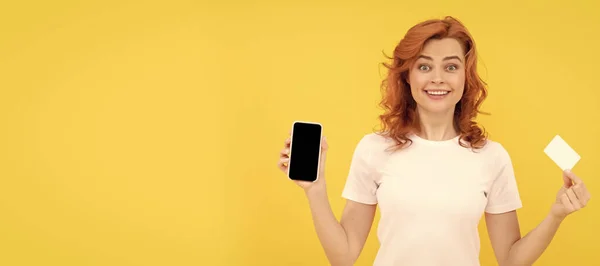 兴奋的年轻女士用持有信用卡的手机隔离了黄色的背景 女子独立人脸肖像 带有模拟复制空间的横幅 — 图库照片