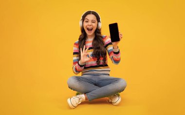 Portrait of cute teenage girl using mobile phone, chatting on web, typing sms message. Mobile app for smartphone. Children lifestyle concept. Mock up copy space
