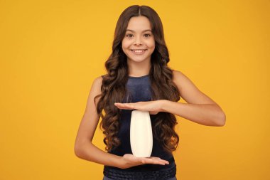 Şampuan kremi kullanan bir çocuk. Günlük kozmetik bakım. 12, 13, 14 yaşlarındaki ergen çocuğun elinde saç ve cilt bakımı şişesi var. Güzellik sağlığı ve kozmetik ürünleri. Mutlu kız yüzü, pozitif ve gülümseyen duygular