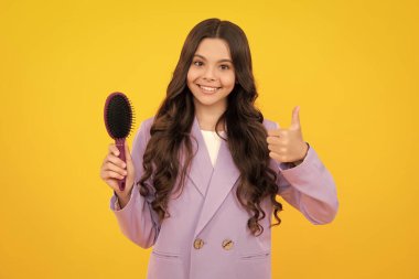 Teenager girl with long hair holding comb hairbrush for combing, beauty. Conditioner shampoo hair. Beauty kids salon. Child hairstyle. Happy face, positive and smiling emotions.