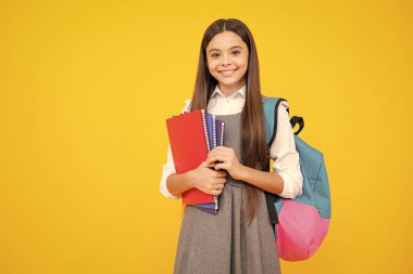 Liseli kız, genç kız, sarı izole stüdyo geçmişi üzerine kitap tutuyor. Okul ve eğitim kavramı. Okula geri dön.