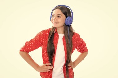 12, 13, 14 yaşlarında komik bir kız. Kulaklıklı müzik dinliyor. Kulaklıklı genç kız kulaklıkla şarkı dinliyor. Mutlu gülümseyen genç kızın portresi.