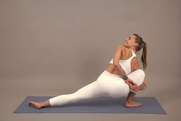 活泼的女孩在瑜伽垫上做运动时 双腿向上抬起 灰色背景 空间广阔 — 图库照片
