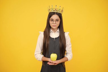 Kraliçe tacındaki genç çocuk sarı arka planda elma tutuyor. Tacın içindeki prenses kız. Genç kız diyabet takıyor.