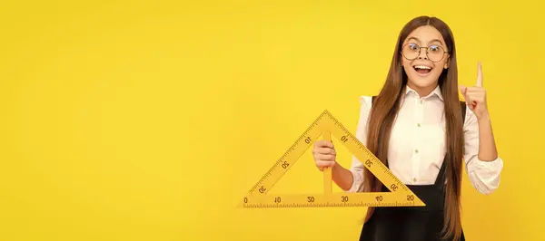 stock image inspired with idea teen girl hold triangle. back to school. algebra and geometry. Portrait of schoolgirl student, studio banner header. School child face, copyspace