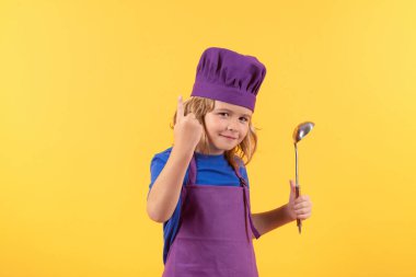 Funny kid chef cook with kitchen ladle, studio portrait. Cooking children. Chef kid boy in form of cook. Child boy with apron and chef hat preparing a healthy meal on studio isolated background