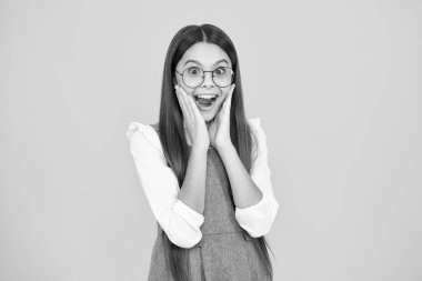 Shocked teenager child girl portrait isolated on yellow background. Excited face. Amazed expression, cheerful and glad