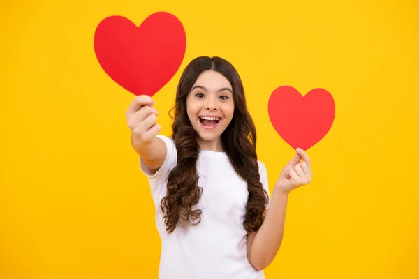 stock image Lovely romantic teenage girl hold red heart symbol of love for valentines day isolated on yellow background. Happy teenager, positive and smiling emotions of teen girl