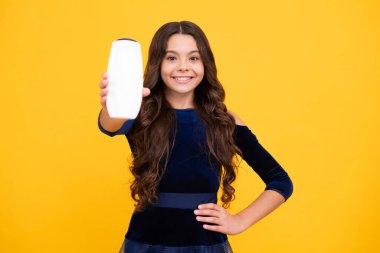 Teenager child girl with bottle shampoo conditioners or shower gel. Kids hair care. Hair cosmetic product, shampoo bottle. Happy face, positive and smiling emotions of teenager girl