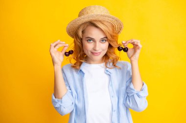 Womans enjoying a fresh sweet cherry. Female eating cherries on yellow background