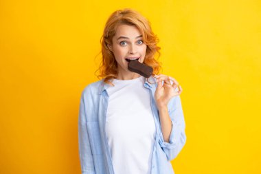 Girl posing with chocolate ice cream on yellow isolated background. Summer woman