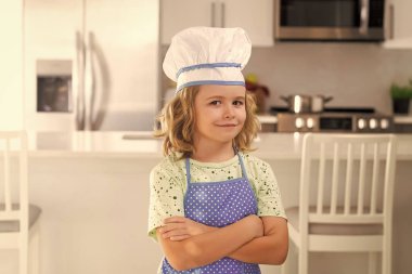 Portrait of funny child chef in kitchen. Children cooking in the kitchen. Funny kid chef cook cookery at kitchen. Chef kid boy making healthy food. Portrait of little child in chef hat