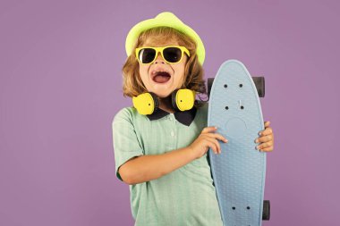 Sıradan giyinen neşeli çocuk elinde uzun pano tutarken mutlu ve heyecanlı görünüyor. Stüdyo kaykaylı çocuğun portresini izole etti.