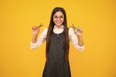 Sarı arka planda izole edilmiş makaslı genç bir kız. Çocuk yaratıcılığı, sanat ve el sanatları