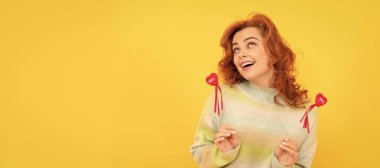 İzole edilmiş yüz portresi, fotokopi alanı olan pankart. Kırmızı kalpli mutlu kızıl kız sarı arka plana yapışıyor. Aşk