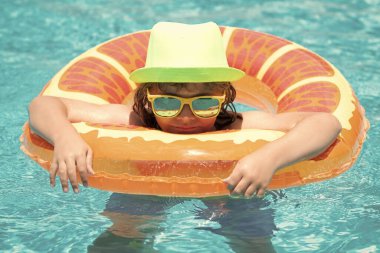 Child boy splashing in swimming pool. Swim water sport activity on summer vacation with children