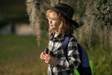 Dürbünlü çocuk doğa yürüyüşü yapıyor. Küçük kaşif. Çocuklarla açık hava eğlencesi ve maceralar. Güneşli kırsal kesimde çocuk turist