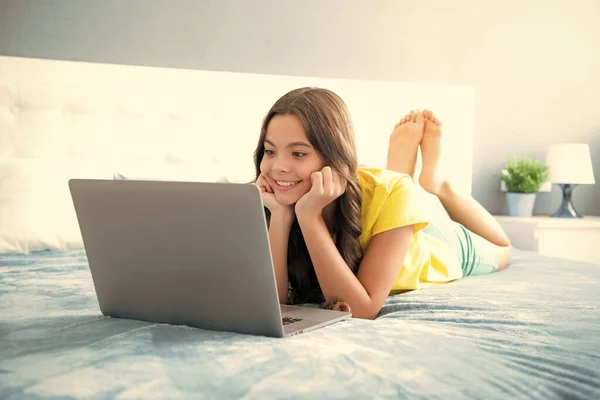 在笔记本电脑上工作的少女躺在床上 躺在卧室里休息 积极向上 面带微笑 — 图库照片