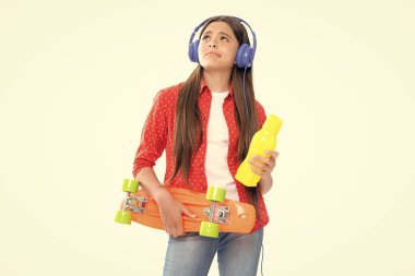 Beautiful and fashion young teen girl posing with skateboard and headphones. Teenager street fashion lifestyle