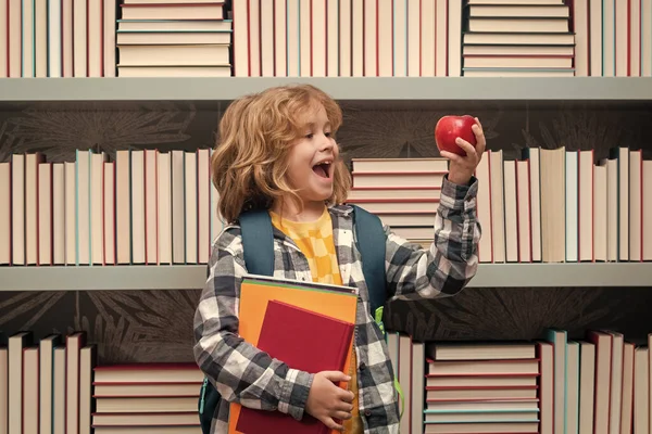 带着书和苹果在图书馆上学的男孩 小学生在小学的教室里学习 在小学课堂上学习的孩子 — 图库照片