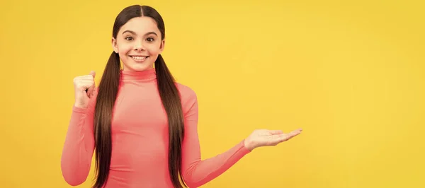 笑顔の子供が製品を発表しコピースペース 黄色の背景に可愛い10代の女の子の広告 子供の顔 水平ポスター 十代の女の子隔離された肖像画 コピースペースのバナー — ストック写真