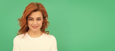 cheerful redhead girl with curly hair on blue background, portrait. Woman isolated face portrait, banner with copy space