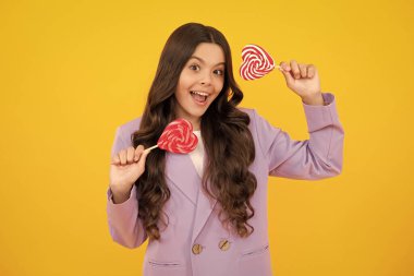 Teenage girl with candy lollipop, happy child 12, 13, 14 years old eating big sugar lollipop, sweets candy. Happy teenager, positive and smiling emotions of teen girl