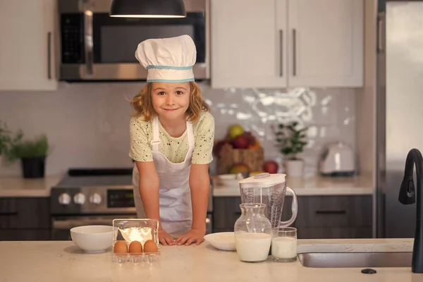 stock image Kid chef cook wearing cooker uniform and chef hat preparing food on kitchen. Cooking, culinary and kids food concept